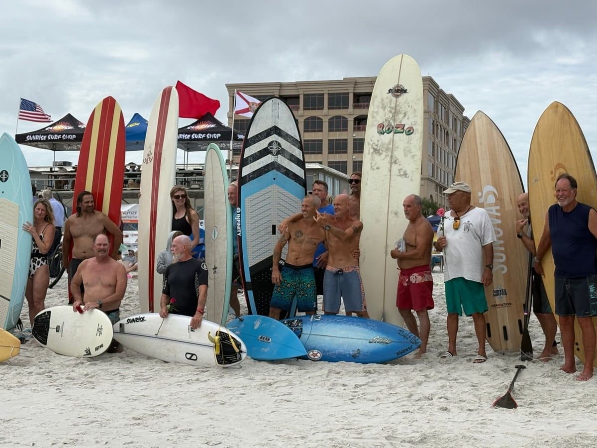 Surfers lined up with their boards on the sand at the Wavemasters Surf Contest