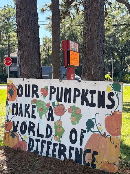 Hand-painted sign reading “Our pumpkins make a world of difference” at Isle of Faith
