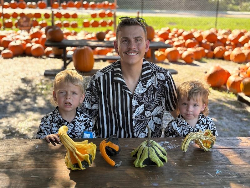 A dad and his two young sons with gourds at the Isle of Faith pumpkin patch